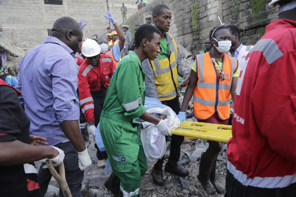 Rescue workers carry a baby rescued from the rubble of a building that collapsed in Tasia Embakasi, an east neighbourhood of Nairobi, Kenya on Friday Dec. 6, 2019. A six-story building collapsed in Kenya's capital on Friday, officials said, with people feared to be trapped in the debris. Police say people have been rescued by residents using their bare hands. (AP Photo/Khalil Senosi)