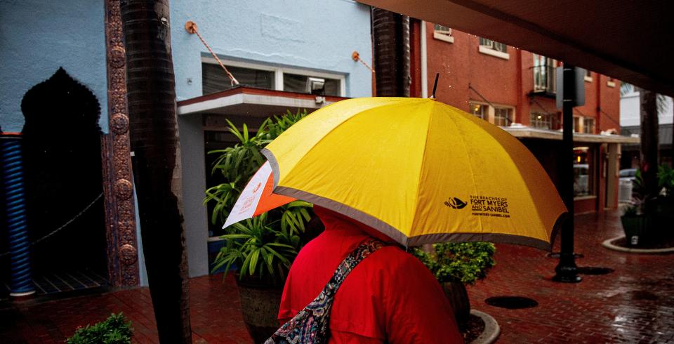 Pedestrians stroll through downtown Fort Myers as rainfall from two interacting low pressure systems drench the area on Wednesday, Nov. 15, 2023.