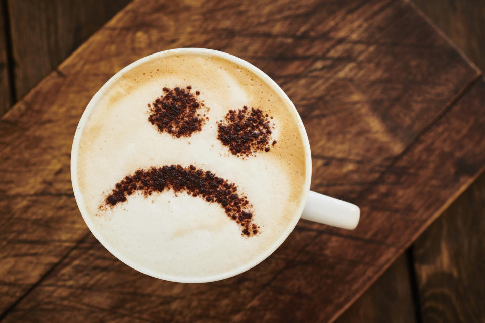 Cappuccino Coffee topped with a chocolate unhappy smiley face.