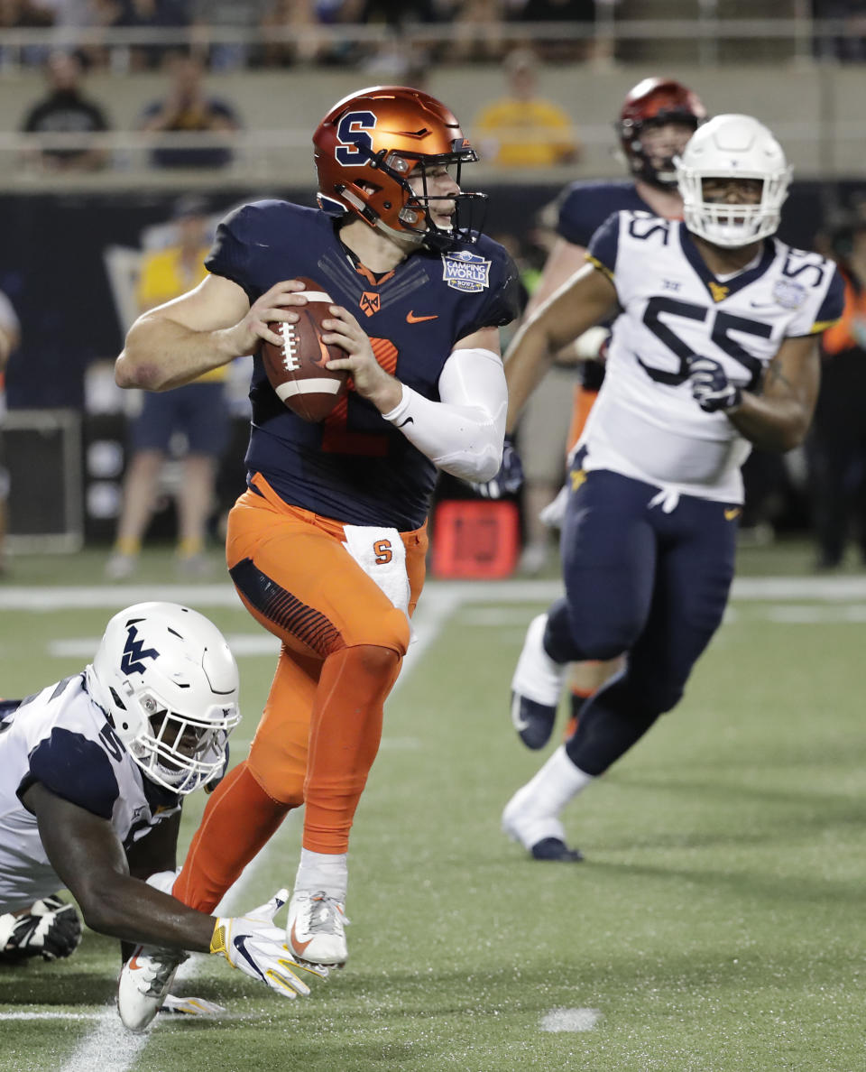 Syracuse quarterback Eric Dungey, center, scrambles as he is pressured by West Virginia defensive lineman Ezekiel Rose, left, and defensive lineman Dante Stills (55) during the first half of the Camping World Bowl NCAA college football game Friday, Dec. 28, 2018, in Orlando, Fla. (AP Photo/John Raoux)