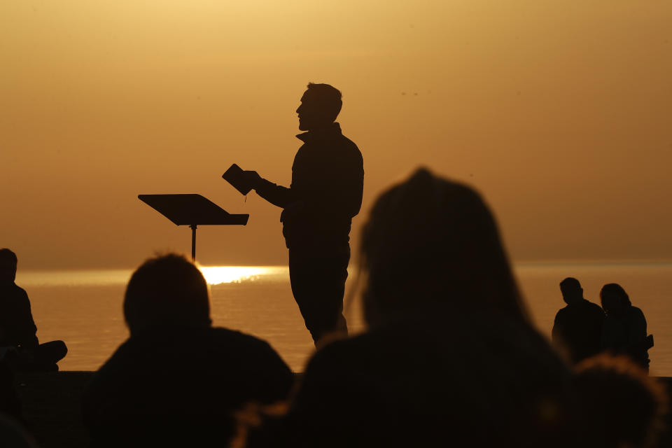 Park Community Church Associate Pastor Trevor Lovell is silhouetted against the sky as he leads an Easter sunrise service while parishioners listen on Sunday, April 4, 2021, at North Avenue Beach in Chicago. (AP Photo/Shafkat Anowar)