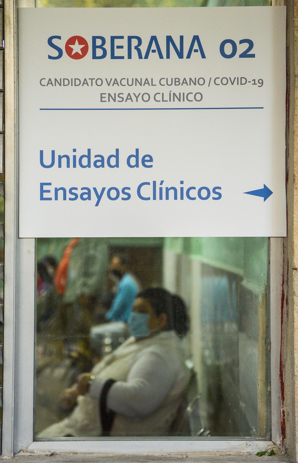 A woman waits behind a sign of the polyclinic where the phase II b of the clinical trial of the Soberana 02 vaccine candidate against Covid-19 is being carried out, in Havana, on January 19, 2021. (Photo by YAMIL LAGE / AFP) (Photo by YAMIL LAGE/AFP via Getty Images)