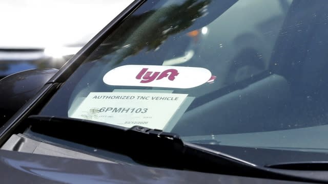 A Lyft rideshare car waits at a stoplight.