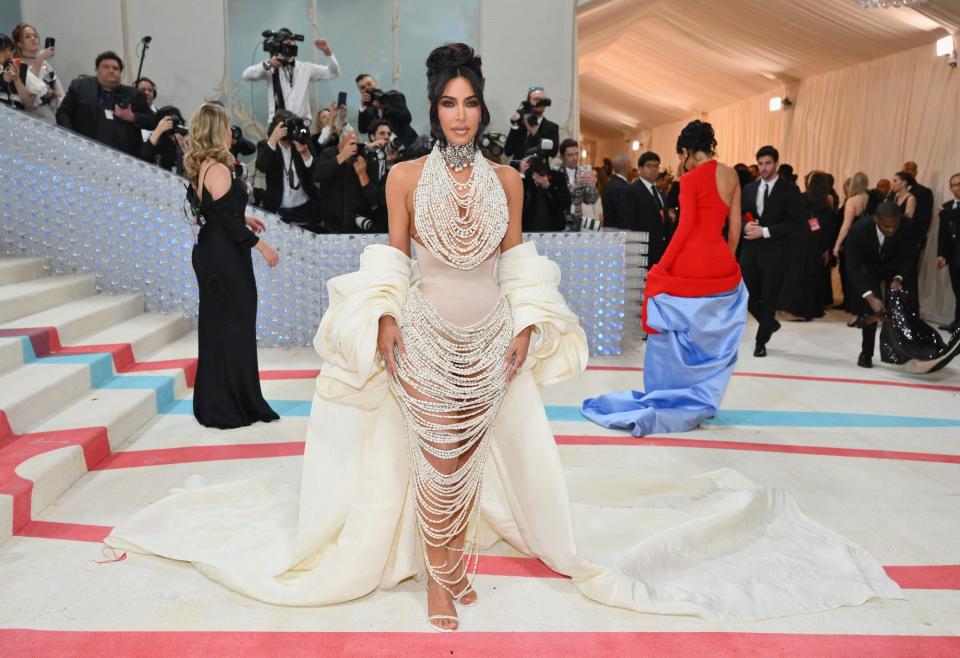 Kim Kardashian poses for photographers at the bottom of the Met Gala's staircase wearing a dress made of stringed pearls.