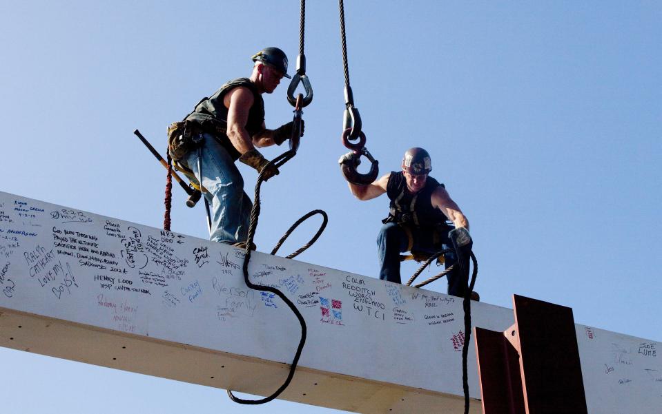 FILE - In this file photo of Aug. 2, 2012, ironworkers James Brady, left, and Billy Geoghan release the cables from a steel beam after connecting it on the 104th floor of One World Trade Center in New York. The beam was signed by President Barack Obama with the notes: "We remember," ''We rebuild" and "We come back stronger!" during a ceremony at the construction site June 14. Also adorned with the autographs of workers and police officers at the site, the beam will be sealed into the structure of the tower, which is scheduled for completion in 2014. (AP Photo/Mark Lennihan, File)