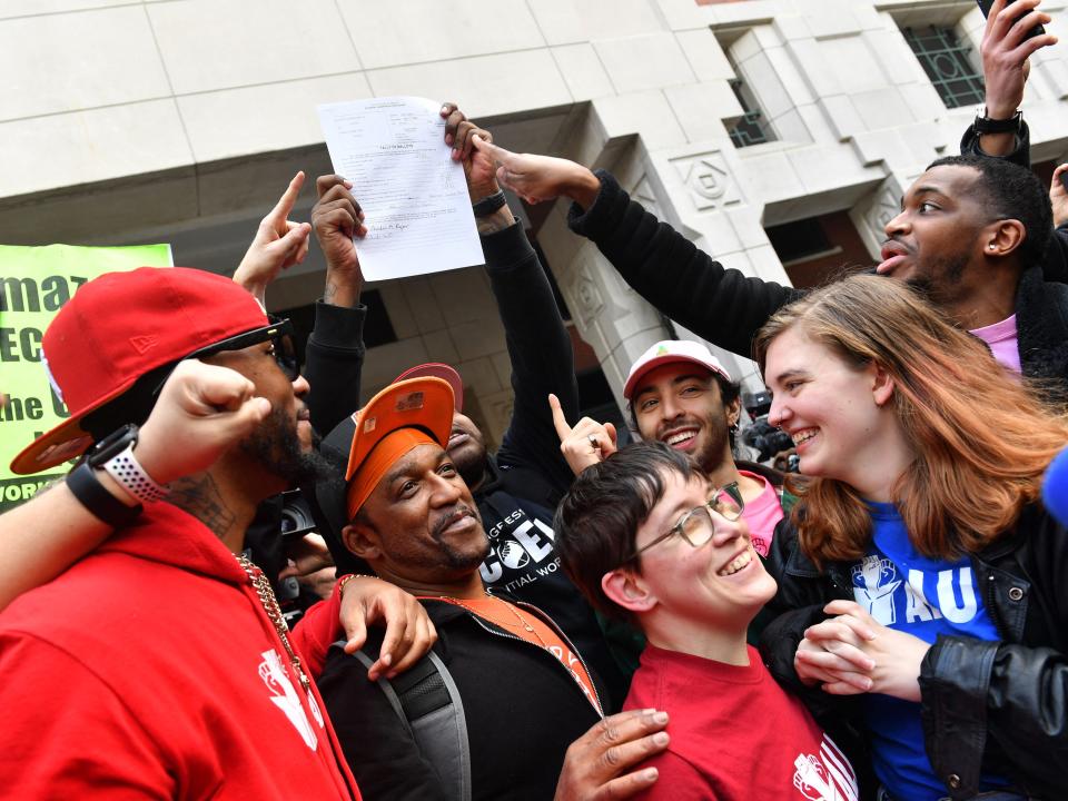 Union organizer Christian Smalls (L) celebrates with Amazon workers following the April 1, 2022, vote for the unionization of the Amazon Staten Island warehouse in New York. - Amazon workers in New York voted Friday to establish the first US union at the e-commerce giant, a milestone for a company that has steadfastly opposed organized labor in its massive workforce. Employees at the Staten Island JFK8 warehouse voted 2,654 to 2,131 in support of the unionizing drive, according to a tally of ballots from the National Labor Relations Board. (Photo by Andrea RENAULT / AFP) (Photo by ANDREA RENAULT/AFP via Getty Images)