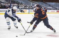 Edmonton Oilers' Connor McDavid (97) gets the shot away as Winnipeg Jets' Derek Forbort (24) defends during the second period of Game 2 of an NHL hockey Stanley Cup first-round playoff series Friday, May 21, 2021, in Edmonton, Alberta. (Jason Franson/The Canadian Press via AP)