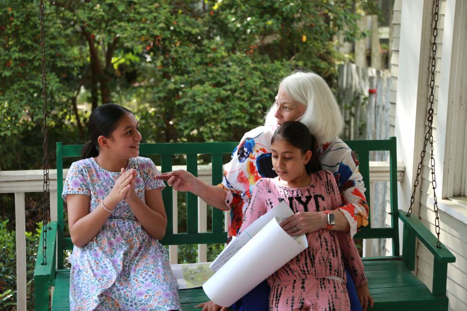 Retired teacher Sissy Hoffman talks with Farahnaz, left, and Marwa about their school work. Farahnaz recently got a 100 on a science project.