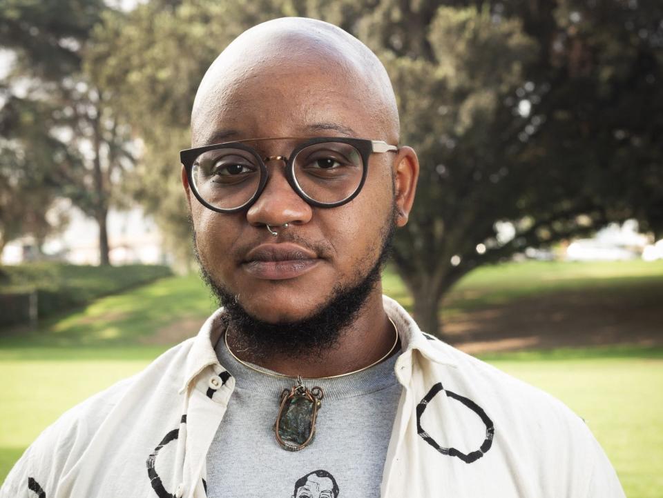 A headshot of Jaden Fields standing outside in front of a field and tree