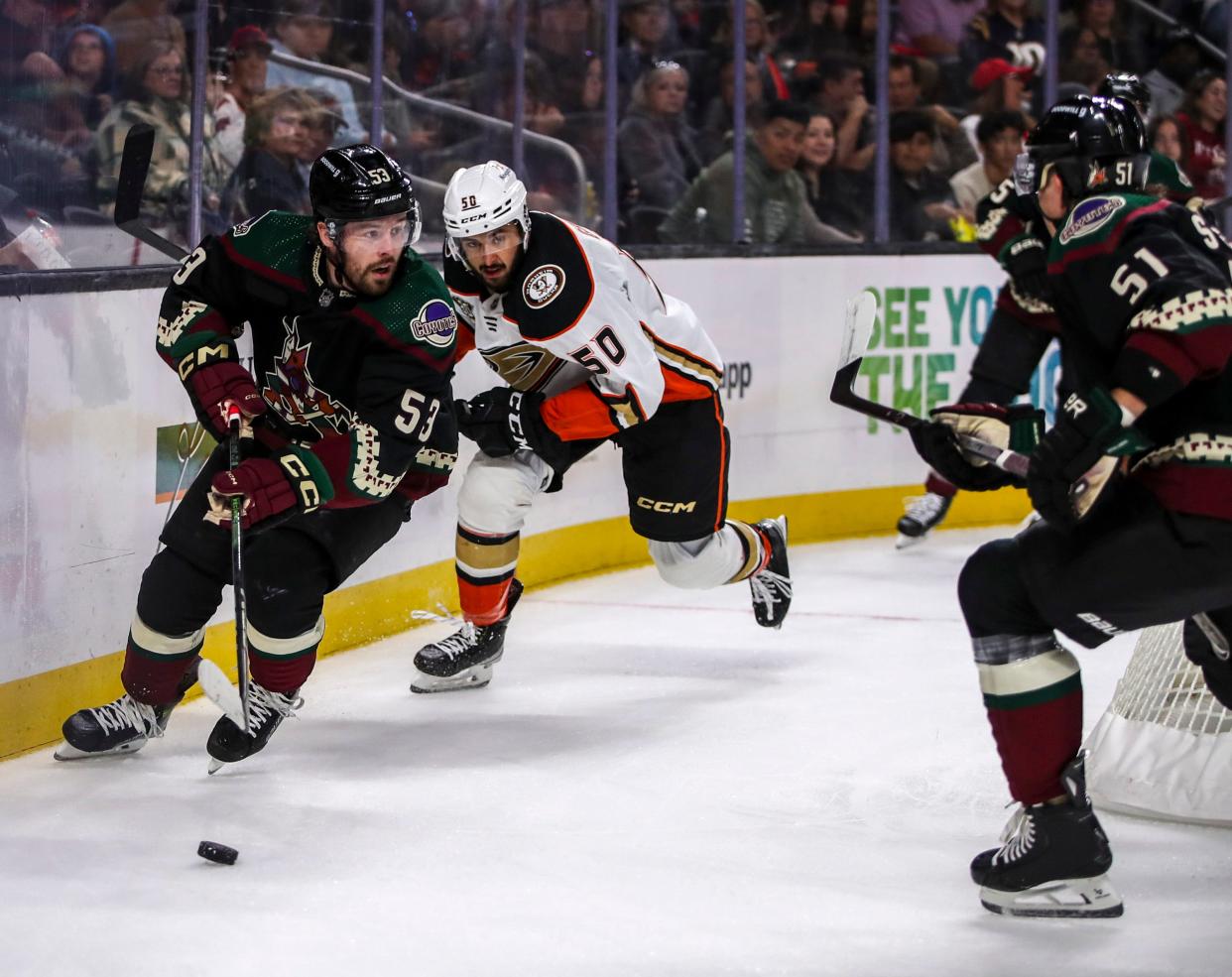 Arizona Coyotes left wing Michael Carcone (53) takes the puck around behind the net with Anaheim Ducks forward Bo Groulx (50) in chase during the first period of their exhibition game at Acrisure Arena in Palm Desert, Calif., Sunday, Oct. 1, 2023.