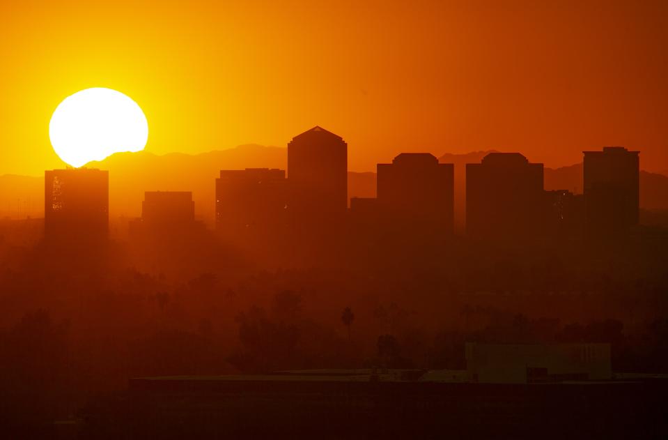 The sun sets over Phoenix on the winter solstice, on a hazy evening, Dec. 21, 2020.