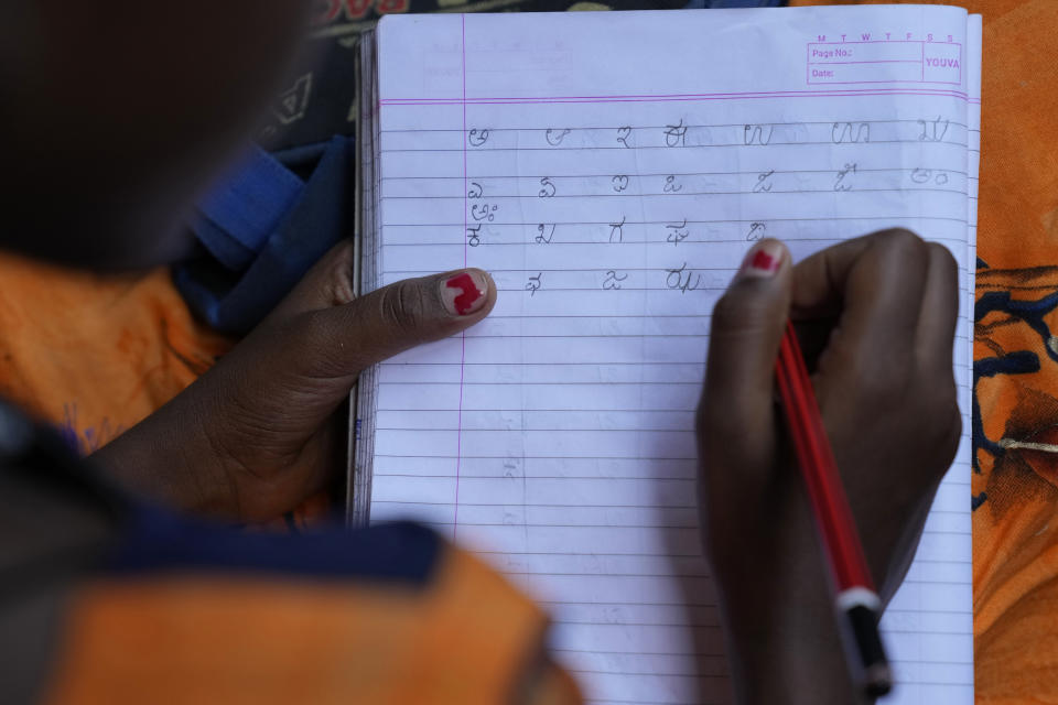 Jerifa Islam writes the alphabet in Kannada in her notebook at a government school in Bengaluru, India, Wednesday, July 20, 2022. A flood in 2019 in the Darrang district of India's Assam started Jerifa, her brother Raju and their parents on a journey that led the family from their Himalayan village to the poor neighborhood. The kids are now learning a new language to be able to go to school, and their parents hope that this new life in a new city will help them provide opportunities. (AP Photo/Aijaz Rahi)