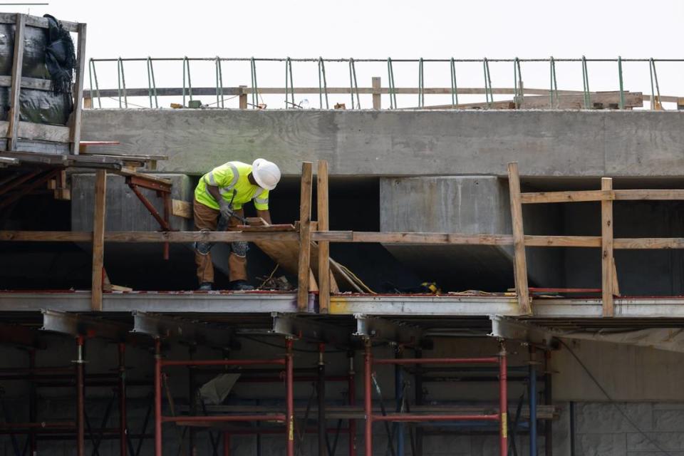 A construction worker in Ballantyne stands on an elevated platform where several top safety railings are missing.