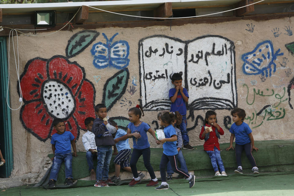 Palestinians sit outside their school in the West Bank Bedouin community of Khan al-Ahmar, Sunday, Oct. 21, 2018. Israeli Prime Minister Benjamin Netanyahu said Sunday he has decided to postpone the planned demolition of a West Bank hamlet to allow time for a negotiated solution with its residents, in a move that appeared aimed at staving off the fierce international condemnation such a demolition would likely entail. (AP Photo/Majdi Mohammed)