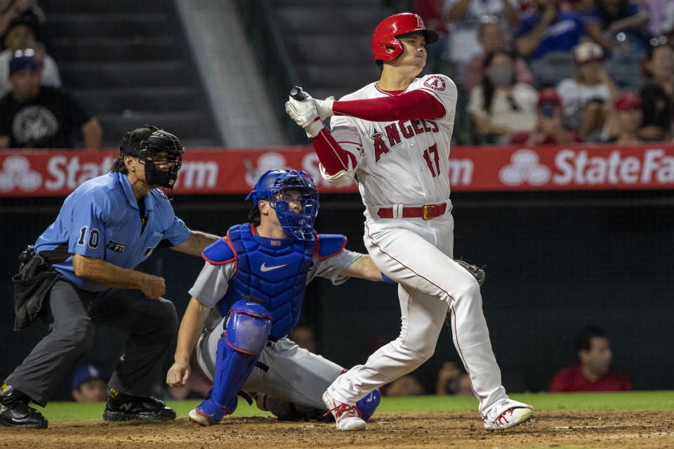 Los Angeles Angels' Shohei Ohtani watches a single next to Los Angeles Dodgers catcher Will Smith and home plate umpire Phil Cuzzi during the sixth inning of a baseball game in Anaheim, Calif., Saturday, July 16, 2022. (AP Photo/Alex Gallardo)