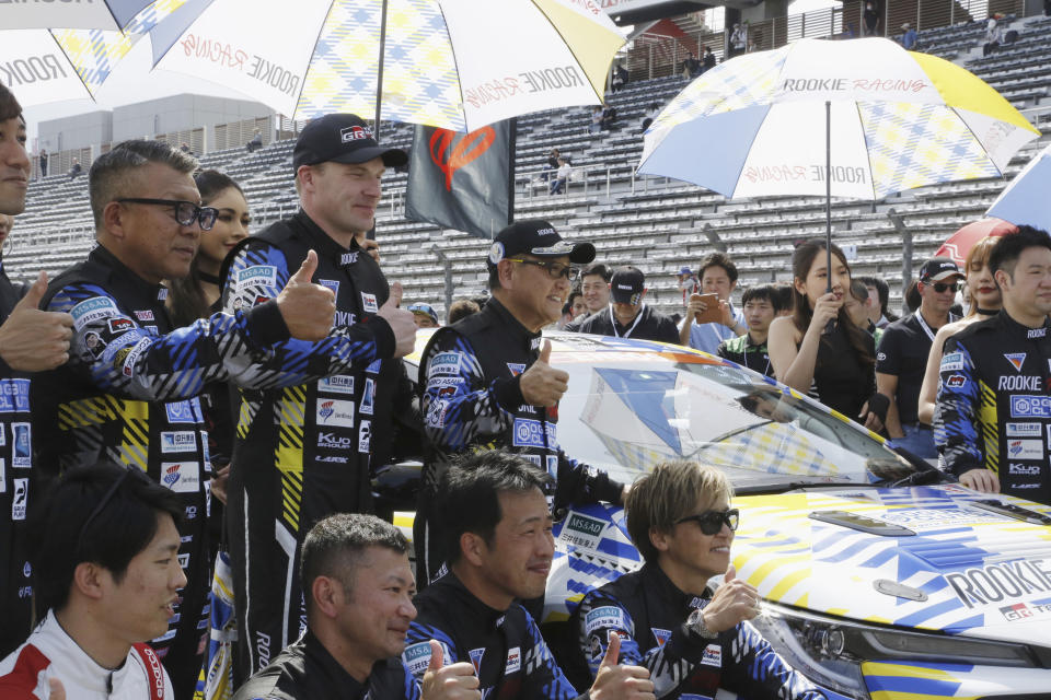 Toyota Chairman Akio Toyoda, center, stands next to the racing car powered by liquid hydrogen he drove during a 24-hour race at Fuji International Speedway in Oyama town, some 100 kilometers (62 miles) southwest of Tokyo, Saturday, May 27, 2023. The hydrogen-fueled Corolla has made its racing debut, part of a move to bring the futuristic technology into the racing world and to demonstrate Toyota’s resolve to develop green vehicles. (AP Photo/Yuri Kageyama)