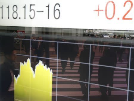 People are reflected on an electronic board showing the Japanese yen's exchange rate against the U.S. dollar outside a brokerage in Tokyo November 20, 2014. REUTERS/Toru Hanai