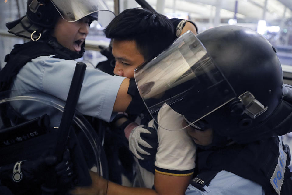 Policemen in riot gears arrest a protester during a demonstration at the Airport in Hong Kong, Tuesday, Aug. 13, 2019. Chaos has broken out at Hong Kong's airport as riot police moved into the terminal to confront protesters who shut down operations at the busy transport hub for two straight days. (AP Photo/Kin Cheung)