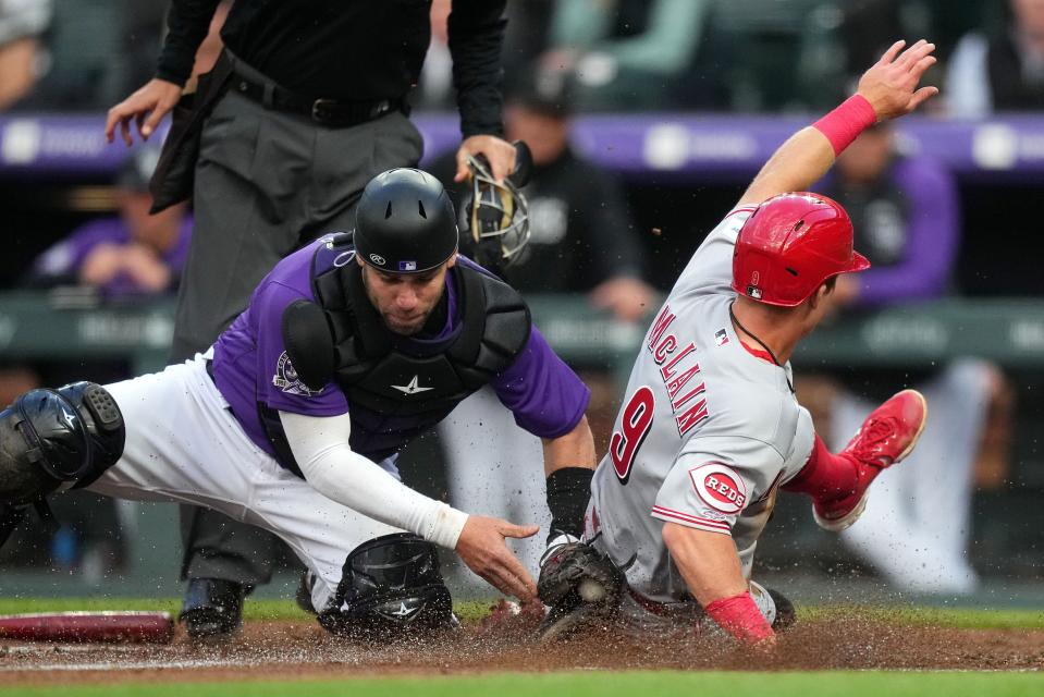 Matt McLain slides past the tag of Austin Wynns in a Reds-Rockies game in Denver last May.