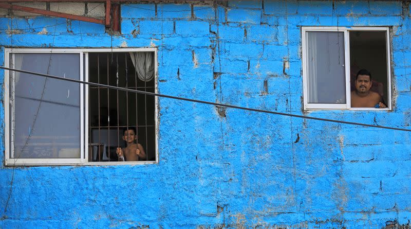 A man and a boy look out from the windows of their home during a curfew imposed by the government amid concerns about the spread of coronavirus disease, in Colombo