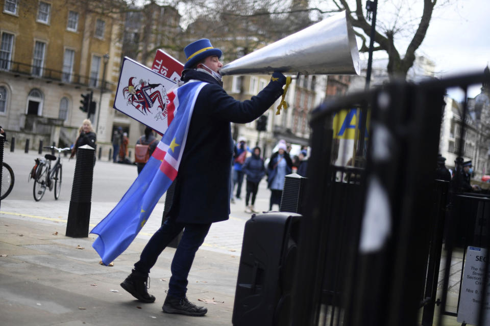 Anti-Brexit protester Steve Bray shouts through an over-sized loud hailer at the gates of Downing Street, London, Thursday, Dec. 24, 2020. Negotiators from the European Union and Britain worked through the night and into Christmas Eve to put the finishing touches on a trade deal that should avert a chaotic economic break between the two sides next week. Trade will change regardless come Jan. 1, when the U.K. leaves the bloc’s single market and customs union. (Victoria Jones/PA via AP)