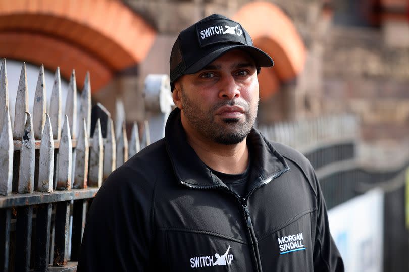 Marcellus Baz, founder and CEO of Switch Up, headshot with black cap and branded Switch Up jacket, stood next to spiky metal fencing with straight face