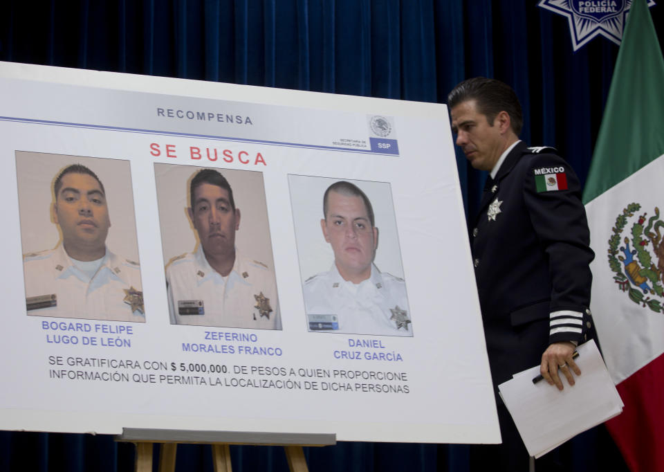 Luis Cardenas, chief of regional security division of the federal police of Mexico, walks behind a poster showing pictures of wanted federal police officers Daniel Cruz Garcia, right, and Zeferino Morales Franco, center, who are accused of allegedly murdering three other officers at Mexico City's international airport, and a third alleged accomplice, federal police officer Bogard Felipe Lugo de Leon, left, at a press conference in Mexico City, Thursday, June 28, 2012. The two federal police officers are suspected of working for drug traffickers and opening fire and killing three policemen in a crowded food court on Monday, June, 25, 2012. All three remain at large. (AP Photo/Esteban Felix)