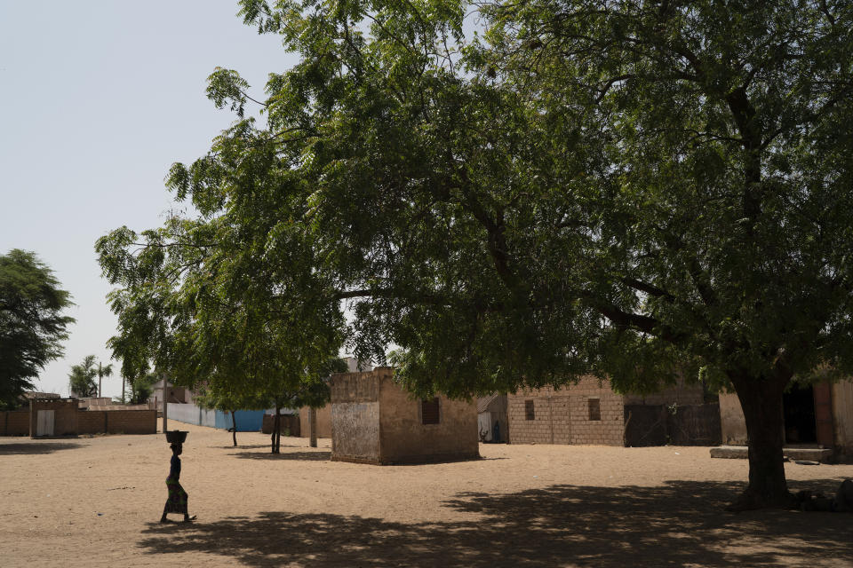 A girl carries a bucket of water from a community well in the village of Ndiawagne Fall in Kebemer, Senegal, on Friday, Nov. 5, 2021. The region is on one end of a project called the Great Green Wall that was once envisioned as a way for Africa to fight climate change. The idea behind the stalled project was to plant a 5,000-mile line of trees that would span the entire continent and hold back the Sahara Desert. (AP Photo/Leo Correa)