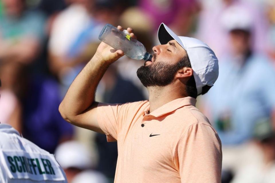 Scottie Scheffler of the United States drinks water on the ninth green.