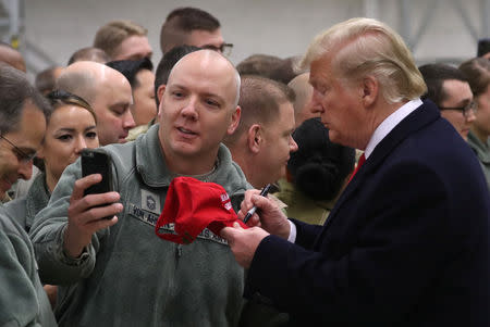 U.S. President Donald Trump signs a hat during a visit to U.S. troops at Ramstein Air Force Base, Germany, December 27, 2018. REUTERS/Jonathan Ernst