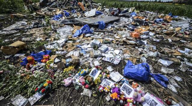 Flowers, soft toys along with pictures are left amongst the wreckage at the site of the crash of a Malaysia Airlines plane. Photo: Getty