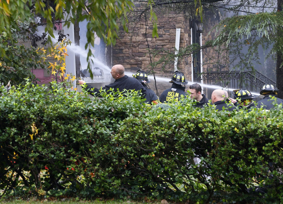 Woodbridge firefighters work to extinguish the scene of a plane crash at a home in Woodbridge, N.J., Tuesday, Oct. 29, 2019. (AP Photo/Noah K. Murray)