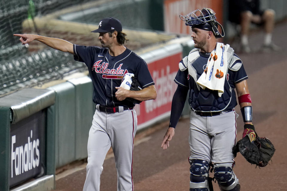 Atlanta Braves starting pitcher Cole Hamels, left, gestures to teammates sitting in the stands while walking with catcher Tyler Flowers to the dugout prior to a baseball game against the Baltimore Orioles, Wednesday, Sept. 16, 2020, in Baltimore. (AP Photo/Julio Cortez)