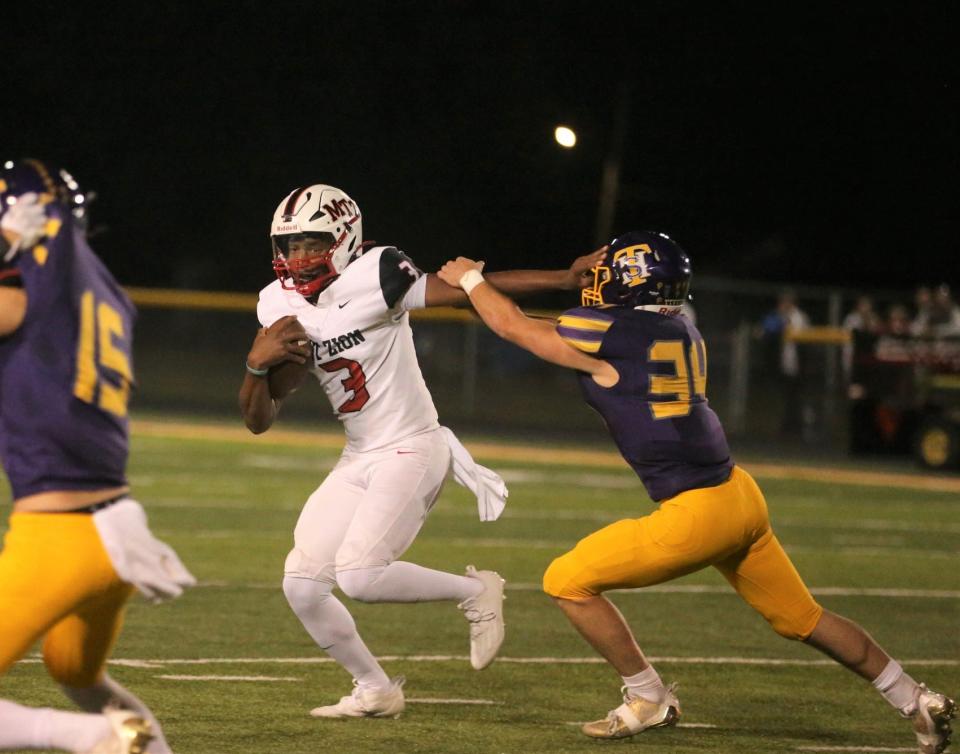 Mount Zion's Makobi Adams stiffs arm a Taylorville defender during an Apollo Conference game at Taylorville on Friday, Sept. 15, 2023.