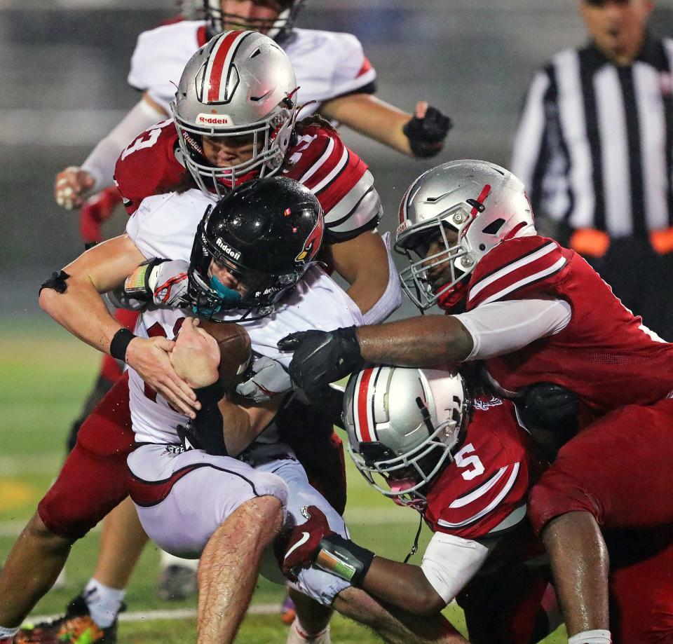 Canfield running back Scottie Eaton, center, is stopped by East linebacker Antonio Rosser (23), linebacker Jaden Bell (5) and defensive lineman Cochise Griffin (51) during the second half of a Division III playoff football game Friday in Akron.