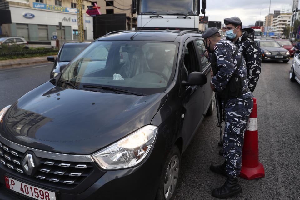 Police officers stand at a checkpoint to inspect cars that violate the lockdown, in Beirut, Lebanon, Thursday, Jan. 14, 2021. Lebanese authorities began enforcing an 11-day nationwide shutdown and round the clock curfew Thursday, hoping to limit the spread of coronavirus infections spinning out of control after the holiday period. (AP Photo / Bilal Hussein)