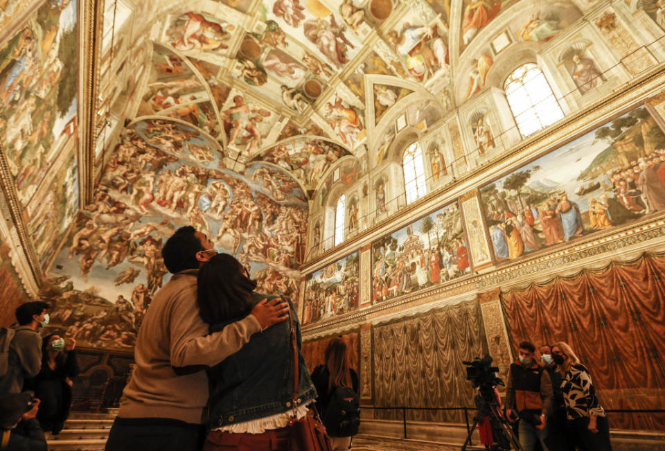 People admire the ornate ceiling and wall frescoes of the Sistine Chapel in the Vatican