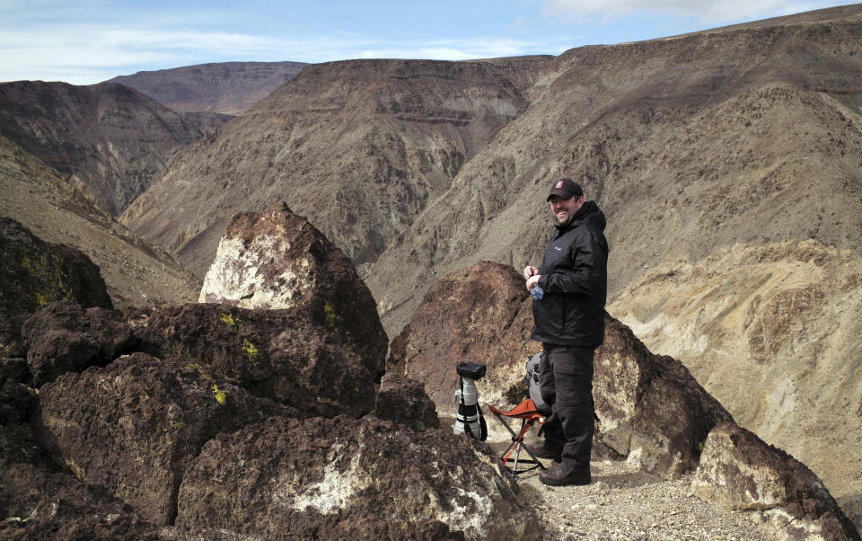 In this photo taken Feb. 28, 2017, photographer Jason O. Watson waits on a cliff overlooking the nicknamed Star Wars Canyon in Death Valley National Park, Calif. Military jets roaring over national parks have long drawn complaints from hikers and campers. But in California's Death Valley, the low-flying combat aircraft skillfully zipping between the craggy landscape has become a popular attraction in the 3.3 million acre park in the Mojave Desert, 260 miles east of Los Angeles.(AP Photo/Ben Margot)