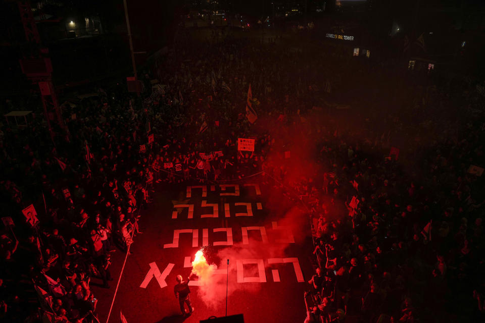 A demonstrator holds up a flare during a protest calling for the release of the Israeli hostages held in the Gaza Strip by the Hamas militant group, in Tel Aviv, Monday, April 29, 2024. (AP Photo/Ohad Zwigenberg)