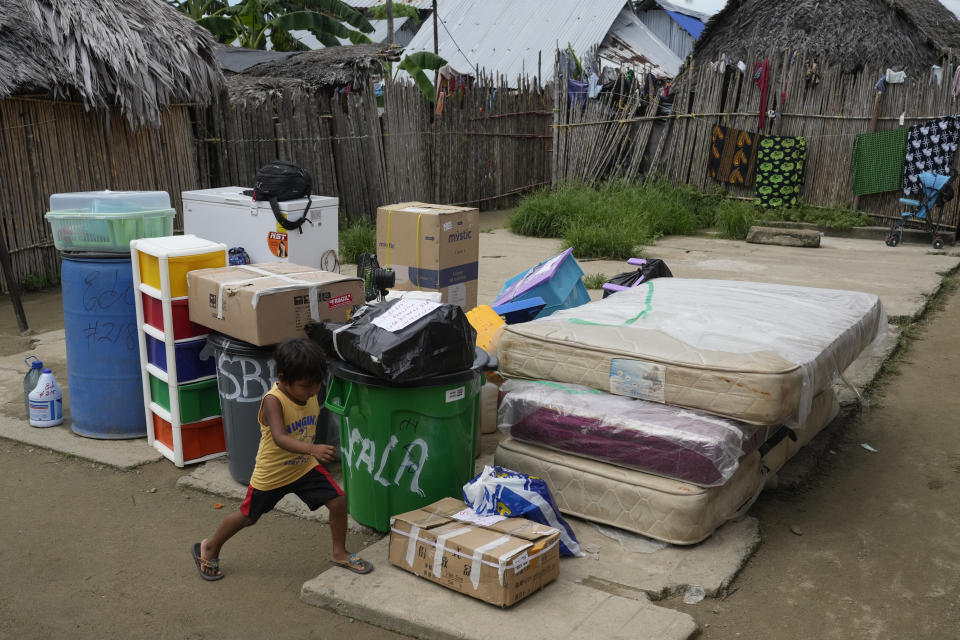 Un joven pasa junto a pertenencias que se trasladan desde la isla de Gardi Sugdub al continente en la costa caribeña de Panamá, el miércoles 5 de junio de 2024. (AP Foto/Matías Delacroix)