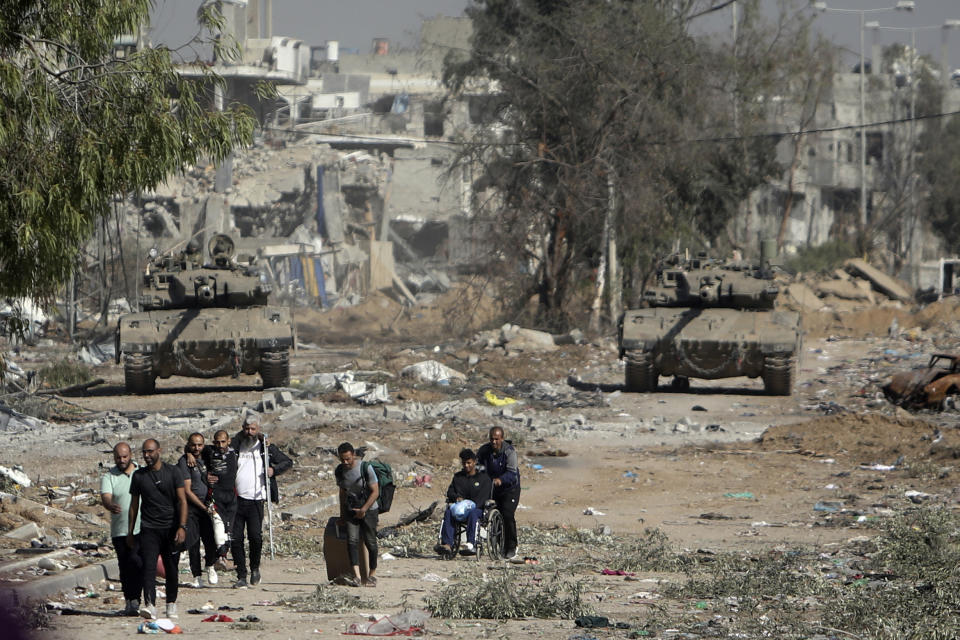 Palestinians flee from northern Gaza as Israeli tanks block the Salah al-Din road in the central Gaza Strip on Friday, Nov. 24, 2023, as the four-day cease-fire in the Israel-Hamas war begins as part of an agreement that Qatar helped broker. (AP Photo/Mohammed Dahman)