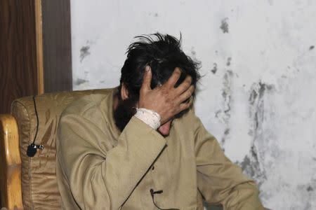 A man, whom the Kurdish People's Protection Units (YPG) said is an Islamic State (IS) fighter of Turkish nationality, hides his face in an interrogation room in Al-Malikiyah (Derek) after being taken captive by the YPG, in Hasaka countryside March 14, 2015. REUTERS/Rodi Said