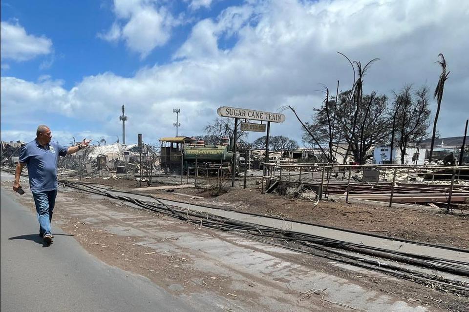 Mayor Richard Bissen walks past the remains of the Sugar Cane Train depot in Lahaina, Hawaii, (AP)