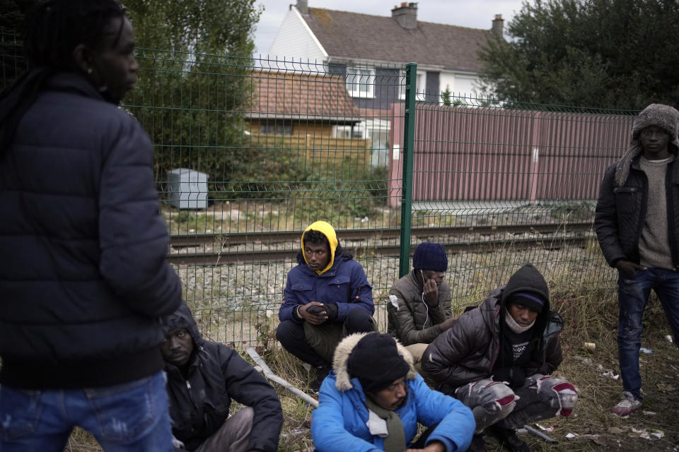 Migrants wait for food distribution at a camp in Calais, northern France, Thursday, Oct. 14, 2021. While some migrants with money can pay to go to Britain on flimsy, overcrowded boats in often dangerous waters, the ones who can’t have to jump on one of the tens of thousands commercial trucks that pass each week between France and Britain. (AP Photo/Christophe Ena)