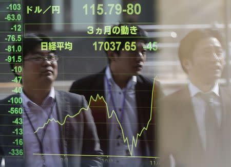 Passers-by are reflected on an electronic board showing Japan's Nikkei stock average and the Japanese yen's exchange rate against the U.S. dollar (top) at a brokerage in Tokyo, November 17, 2014. REUTERS/Issei Kato