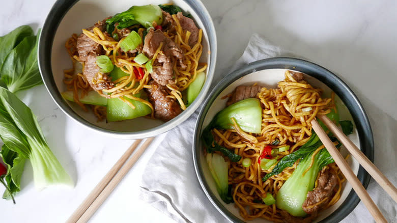 two bowls of beef stir-fry with chopsticks