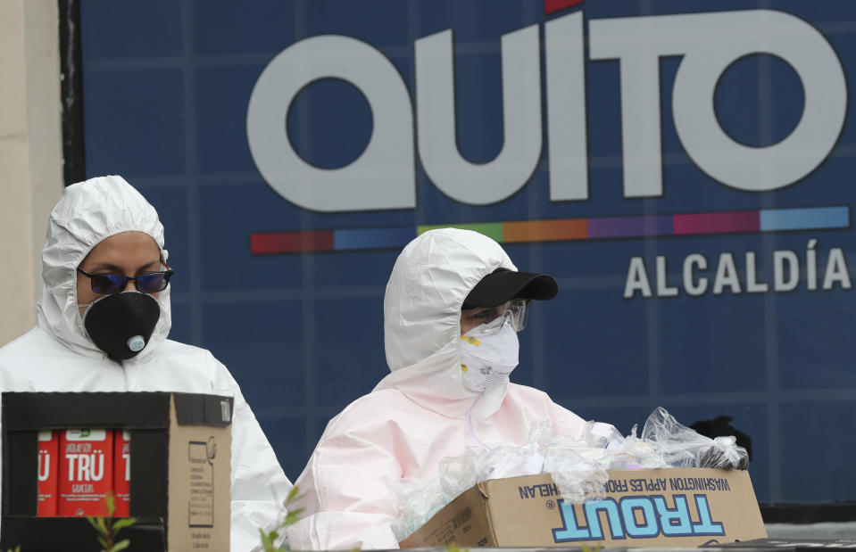 Municipal workers wearing protection gear against the spread of the new coronavirus, carry food and supplies to be distributed to the poor neighborhoods of Quito, Ecuador, Tuesday, March 31, 2020. The government has declared a "health emergency," restricting movement to only those who provide basic services, enacting a curfew, and closing schools. COVID-19 disease causes mild or moderate symptoms for most people, but for some, especially older adults and people with existing health problems, it can cause more severe illness or death. (AP Photo/Dolores Ochoa)