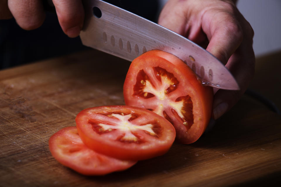 Tomato being sliced with a sharp knife