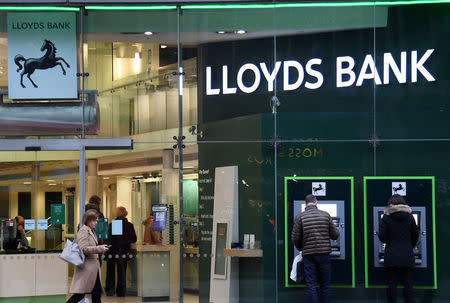 FILE PHOTO: Customers use ATMs at a branch of Lloyds Bank in London, Britain, February 21, 2017. REUTERS/Toby Melville/File Photo