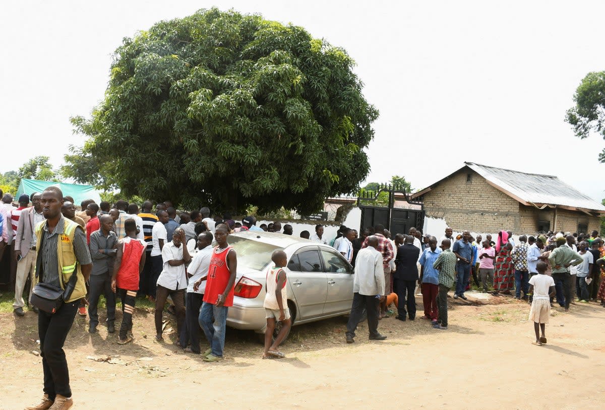 Families wait for news outside the school in Mpondwe  (Reuters)